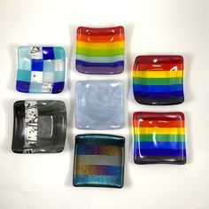 six different colored glass plates on a white surface with a rainbow design in the middle