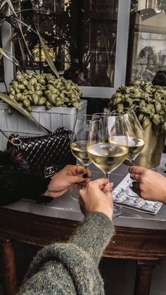 two people sitting at a table with wine glasses on top of it and money in front of them