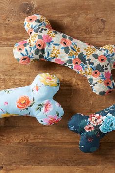 three dog bone shaped cushions sitting on top of a wooden table