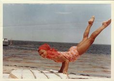 a woman doing a handstand on the beach