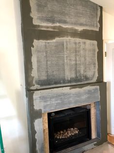 a fire place in the middle of a room being remodeled with gray paint and wood