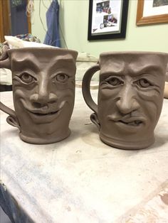 two mugs with faces made to look like they are being used as coffee cups