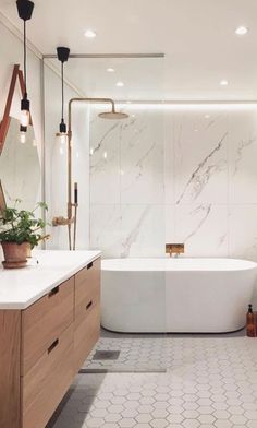 a white bath tub sitting next to a wooden cabinet in a bathroom filled with plants