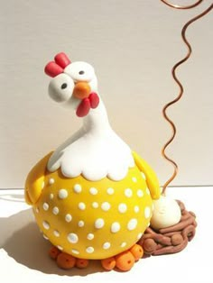 a yellow and white ceramic chicken sitting on top of a brown nest with eggs in it