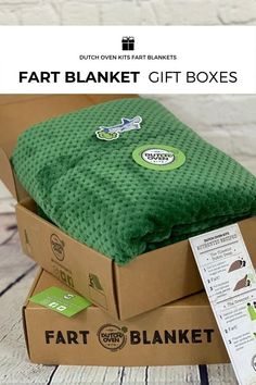 a green blanket sitting on top of a box next to a tag that says fart blanket gift boxes