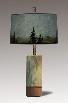 a table lamp with a painting on the side of it and a wooden base underneath