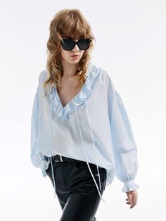 MO&Co. Women's Loose Ruffled Trim Blouse Crafted from a blend of cotton and silk, this blouse features billowy sleeves with delicate ruffled cuffs and a V-neckline with a self-tie design. The loose silhouette pairs perfectly with high-waisted jeans for a chic, effortless look. Features : - Flowy regular fit- Volume sleeves with ruffled cuffs- V neckline with self-tie straps and ruffles details- Made a silk and cotton fabric, slightly sheer effect Code: MBD1TOP026The back length of size S is 68.5 Volume Sleeves, Billowy Sleeves, Ruffle Sleeve Blouse, Tie Design, Flowy Blouse, Blue Blouse, High Waist Jeans, Ruffles, Ruffle Blouse