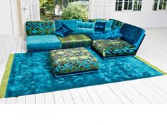 a large blue couch sitting on top of a wooden floor next to a green rug