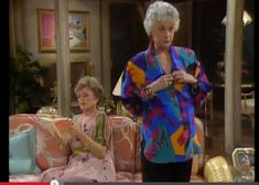 an older woman standing in front of a couch next to another woman sitting on a chair