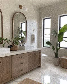 a bathroom with two sinks, mirrors and plants