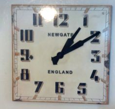 a square clock with the words newgate in black and white on it's face