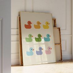 an art print with rubber ducks on it in front of a white wall and wooden floor