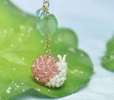 a pink and white beaded necklace on a green leaf