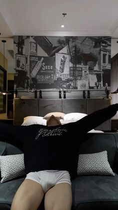 a woman laying on top of a couch in front of a black and white wall