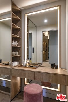 a dressing table with a stool and mirror in the corner, next to it is an illuminated shelf