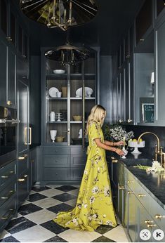 a woman in a yellow dress is standing at the kitchen counter