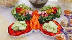 a butterfly shaped platter filled with veggies and other foods on a table