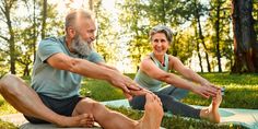 an older man and woman doing yoga in the park