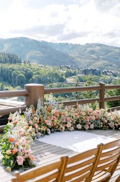 an outdoor ceremony setup with flowers and greenery on the side of a wooden deck