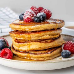 stack of pancakes topped with berries and syrup