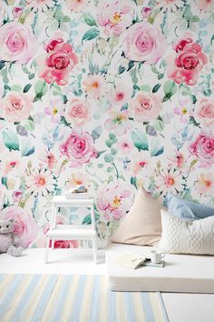 a white bed sitting next to a wall covered in pink and green flowers on top of it