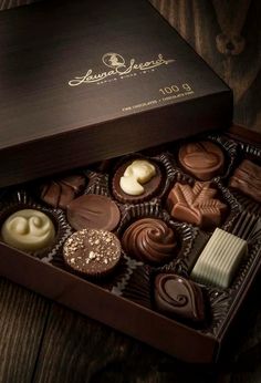 a box of assorted chocolates sitting on top of a wooden table