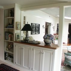 a living room filled with furniture and a lamp on top of a wooden countertop