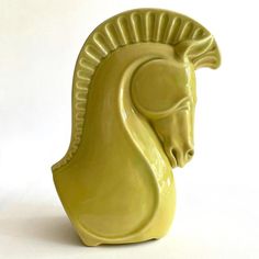 a yellow ceramic sculpture of a horse's head on a white background with long horns