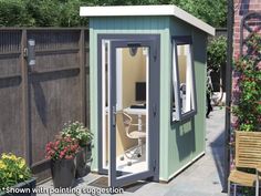 a small garden shed sitting next to a wooden bench and flower potted planter