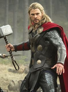 thor is holding an ax in his hand and looking at the camera while another man stands behind him