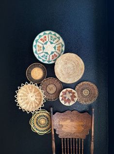 a wooden chair sitting in front of a wall with baskets on it's back