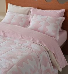 a bed with pink sheets and pillows on it