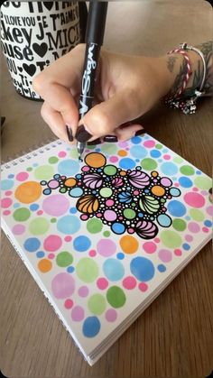 a person is drawing on a notebook with a marker and some polka dot paper in front of them