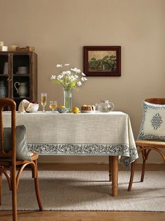 a dining room table with two chairs and a vase filled with flowers