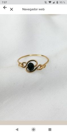 a gold ring with a black stone in the middle on a white cloth background that reads, navegador web