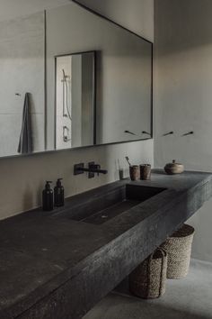 a bathroom sink sitting under a large mirror next to a wooden shelf with two baskets on it