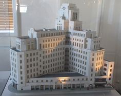 a model of a large building on display in a glass case with white walls and windows