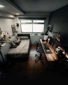 a room with a bed, desk and computer on the table in it's corner