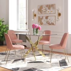 a dining room table with pink chairs and a rug on the floor in front of it