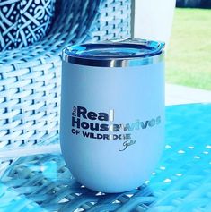 a white cup sitting on top of a blue table next to a wicker chair