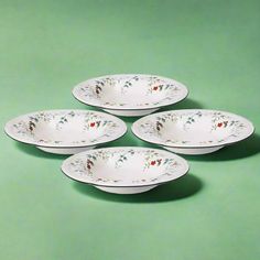 four white plates sitting on top of a green surface