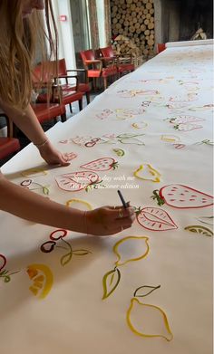 a woman is drawing on a large table cloth