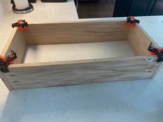 a wooden box sitting on top of a white counter next to a knife holder with orange handles