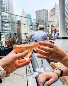 two people toasting with wine glasses in front of cityscape and skyscrapers