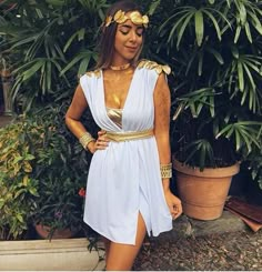 a woman in a white dress standing next to some plants and potted planters