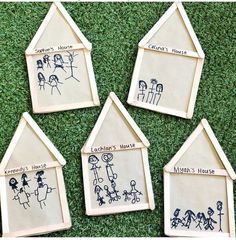 four wooden houses with family drawings on them sitting in the grass, one is for children's house