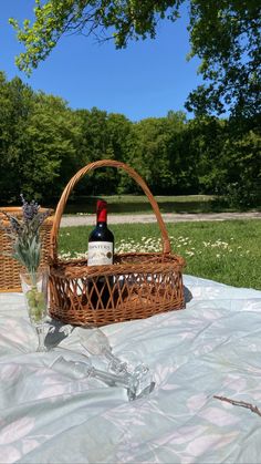 a bottle of wine in a wicker basket on top of a blanket with flowers