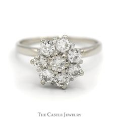 a white gold and diamond cluster ring, with the center stone surrounded by smaller round diamonds