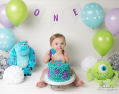 a baby sitting in front of a cake surrounded by balloons