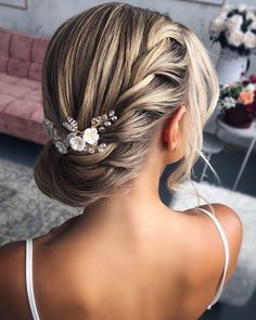 a woman with blonde hair in a low bun wearing a flowered headpiece and white dress